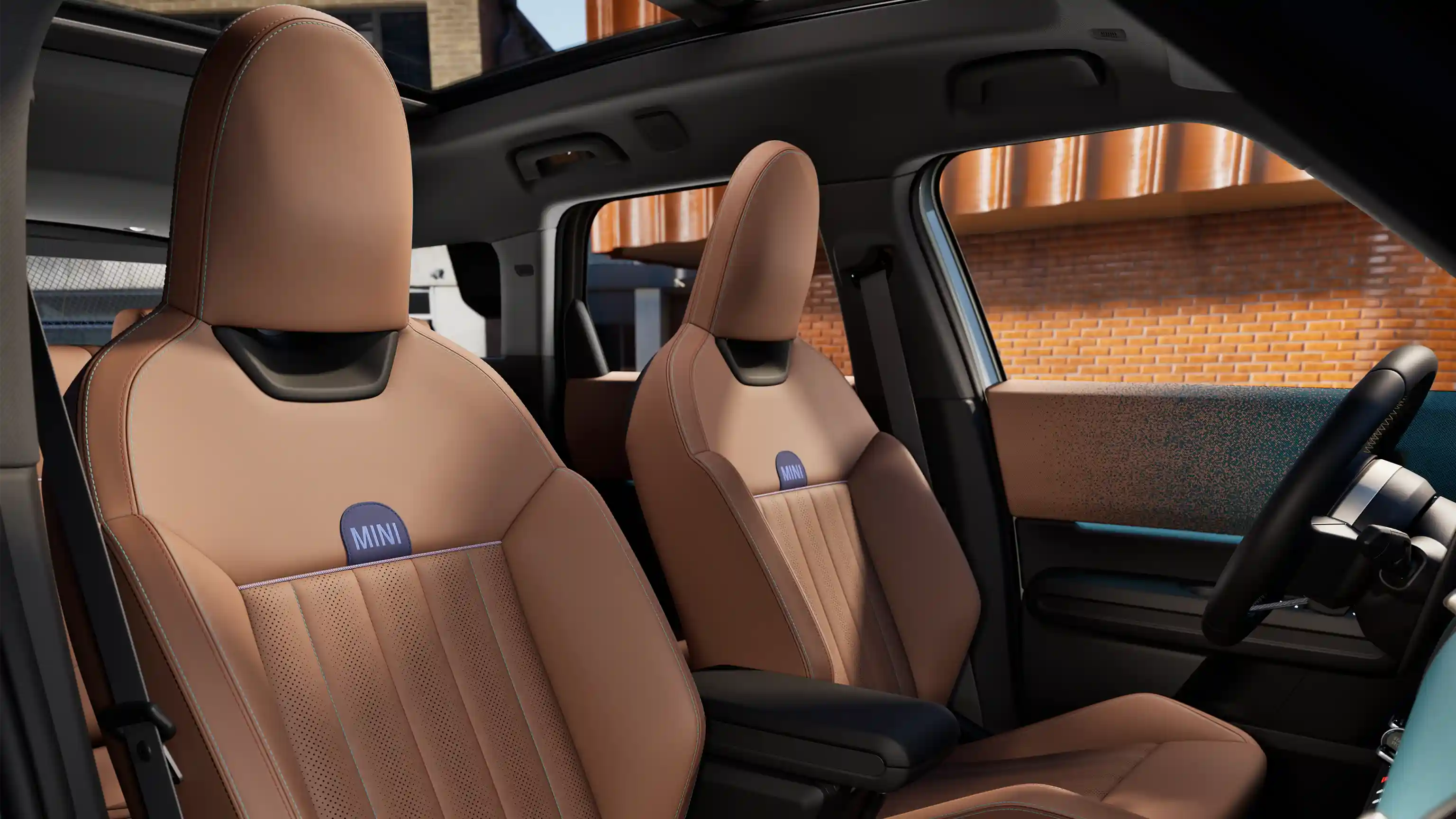 Interior perspective of the MINI Countryman showing the dashboard, steering wheel, round display, panorama glass roof and back of the front seats.