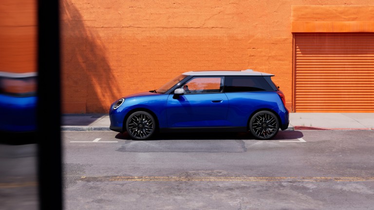 all-electric MINI Cooper side shot by orange wall