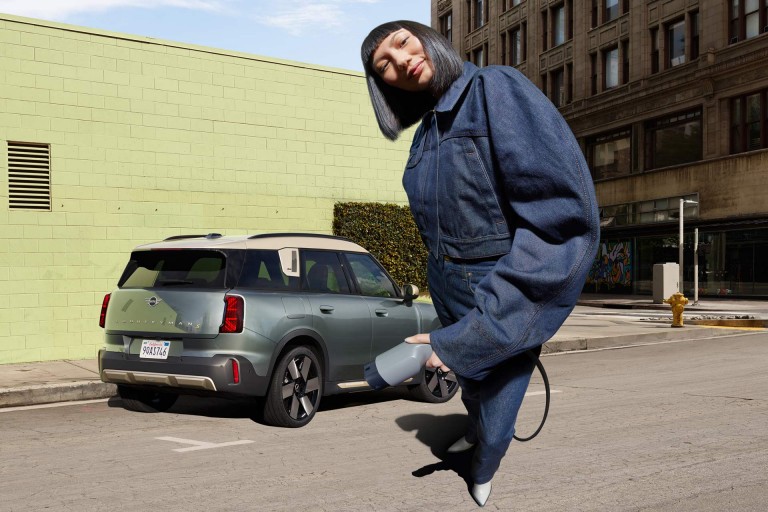 MINI Countryman parked with woman in front, holding a charger